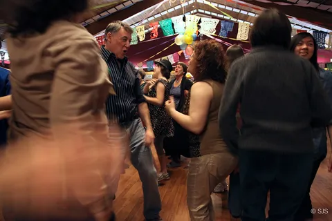 A crowd dances together in a decorated hall strung with colorful paper banners (David and Sharon)