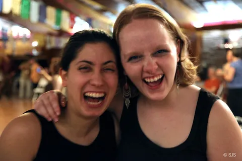 Two young women laugh together, cheek to cheek, in close-up portrait (From left to right: Sophia and Rain)